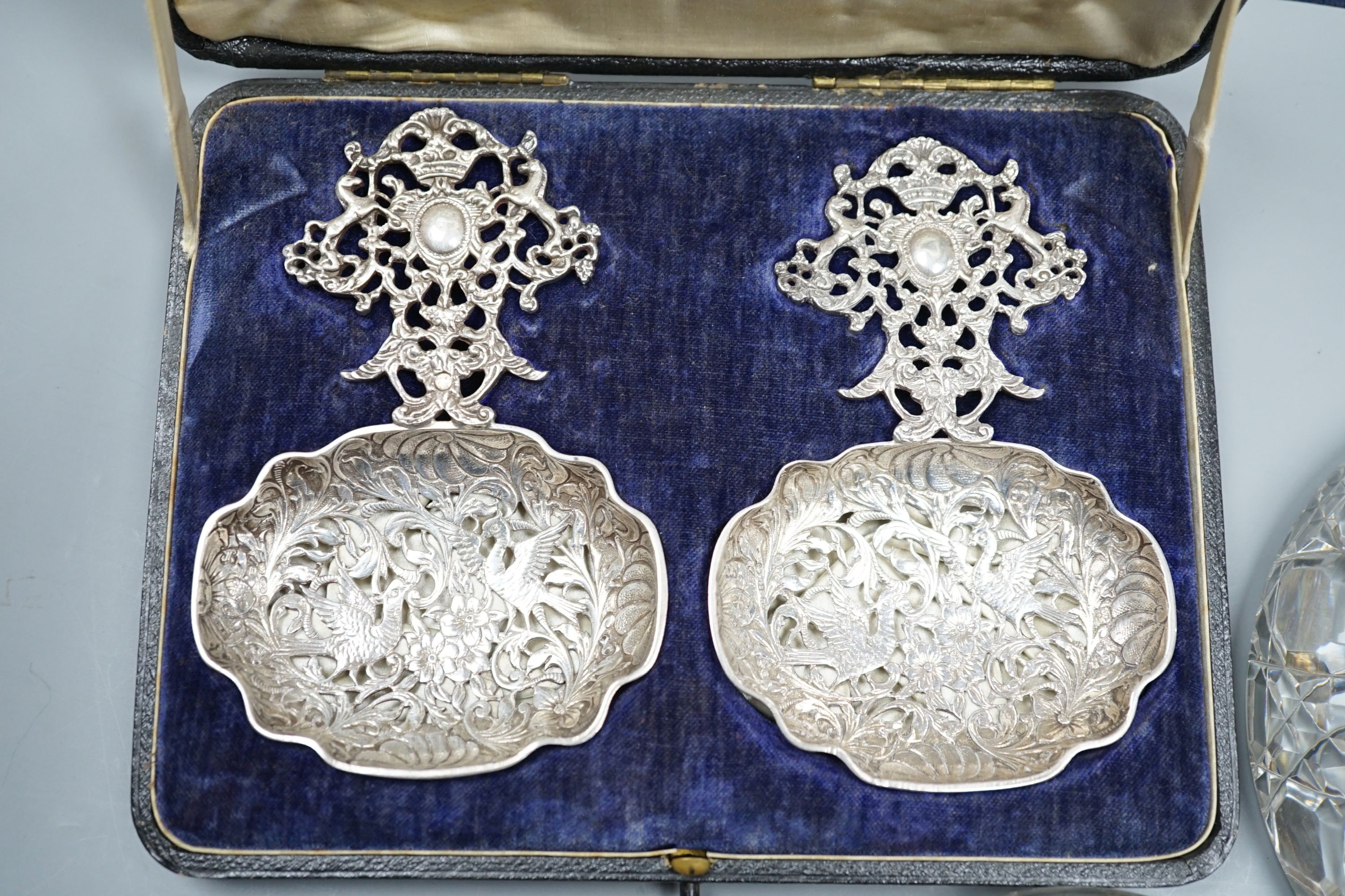 An Edwardian pierced silver mounted glass inkwell, London, 1901, 13.2cm, a silver and green guilloche enamel mounted glass powder jar and a cased pair of early 20th century ornate pierced silver spoons.